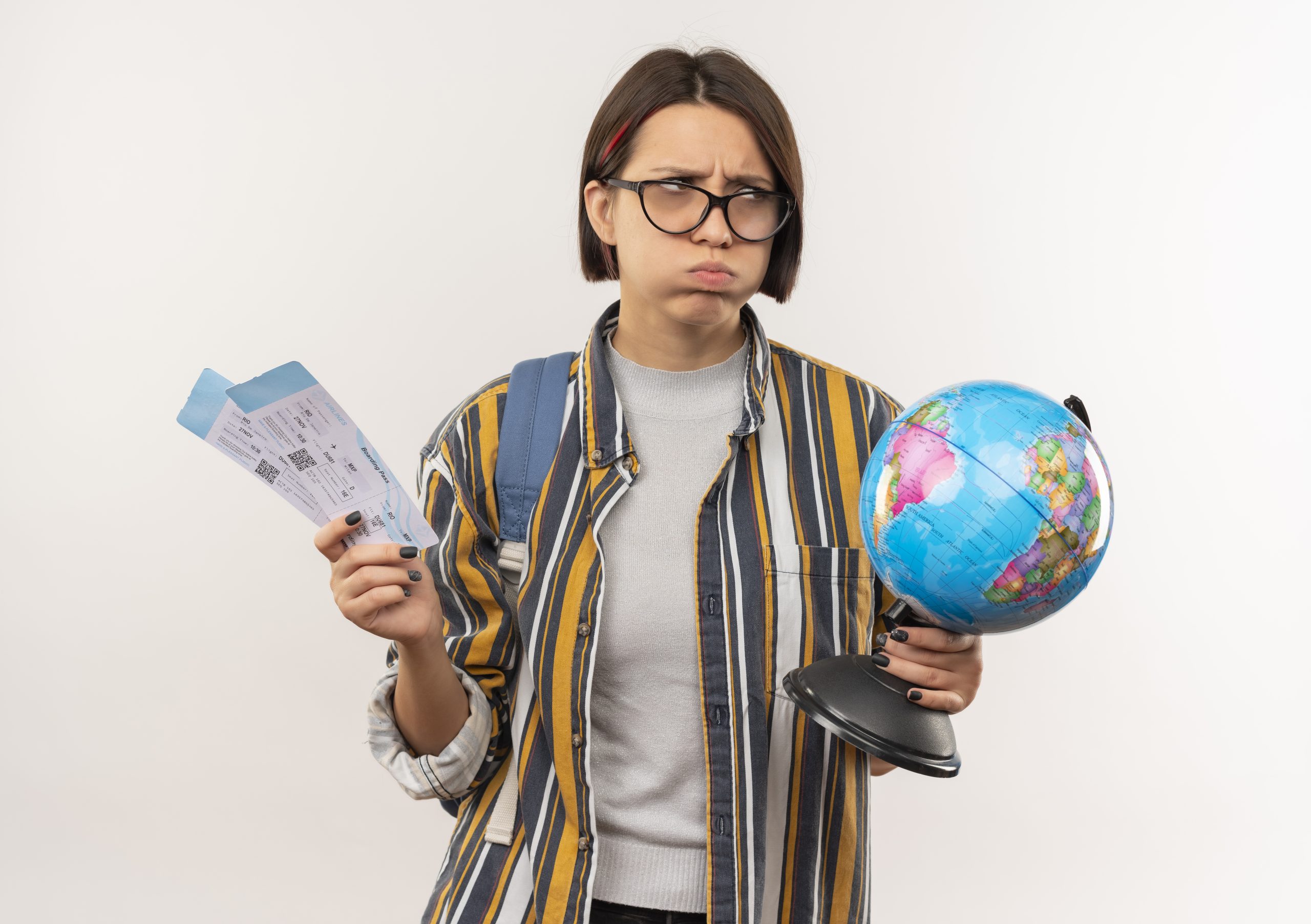 unpleased young student girl wearing glasses and back bag holding airplane tickets and globe looking at side isolated on white background